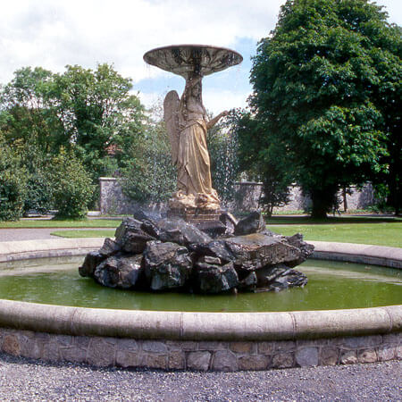 an angelic statue stands in the centre of a circular fountain