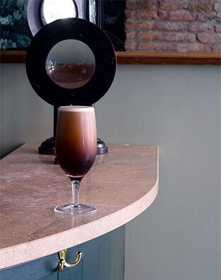 a creamy stout sits in a cocktail glass on the bar