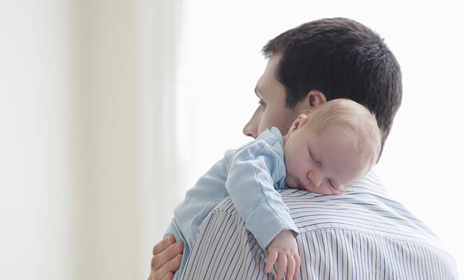 Man carrying baby against shoulder