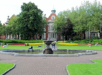 grey fountain, yellow flowers and green grass at st patricks park