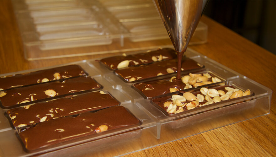 vegan chocolate is poured over peanuts in moulds