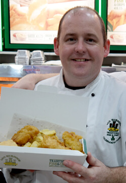 darren salmon wear white chef's coat and holds a takeaway box