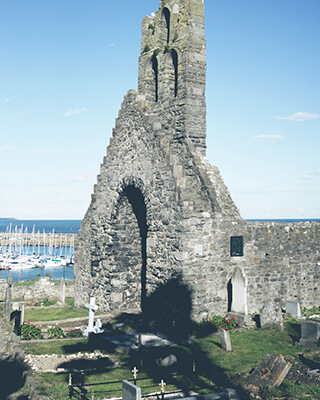 the ruins of an old stone church and grave yard contrast with the yacht filled sea