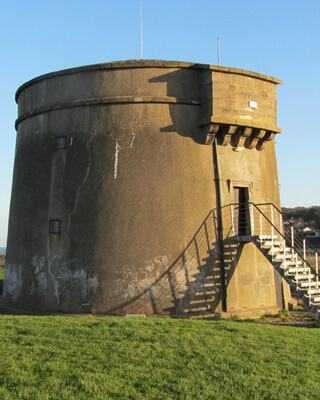 sun shines on the grey, granite martello tower in howth