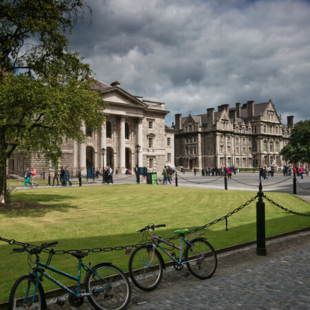 image of old college building with columns behind green grass patch in trinity college dublin
