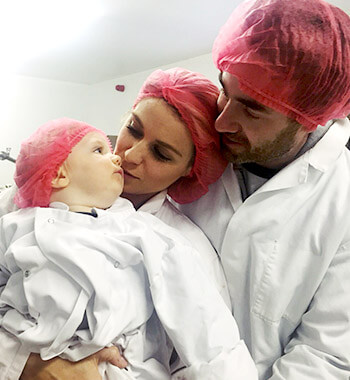 rachel, brian and their son sam wear pink hairnets and white chef coats