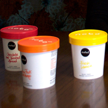 three colourful tubs of nobó ice-cream sit on a wooden table