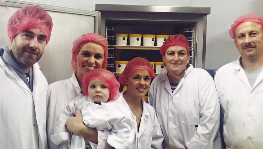 members of the nobó team wear white chef coats and pink hair nets in the kitchen