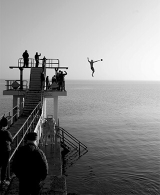 the silhouette of a student diving into the sea