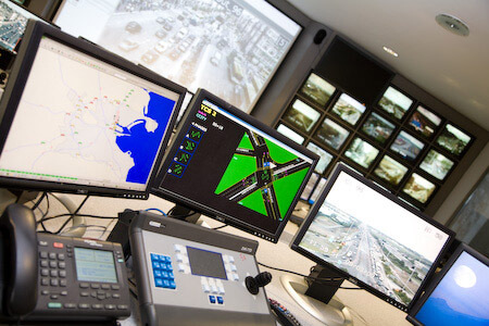 multiple computer screens show maps and different views of the city's roads