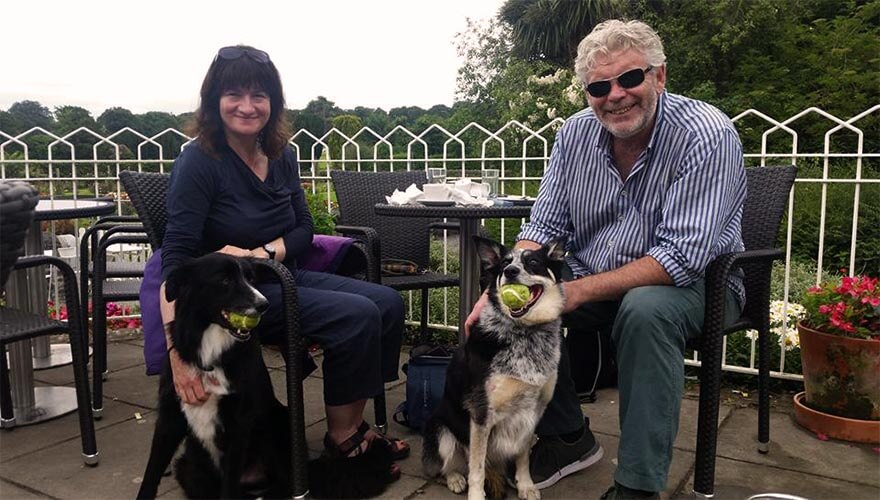two people sit outside the castle tearooms with their dogs 